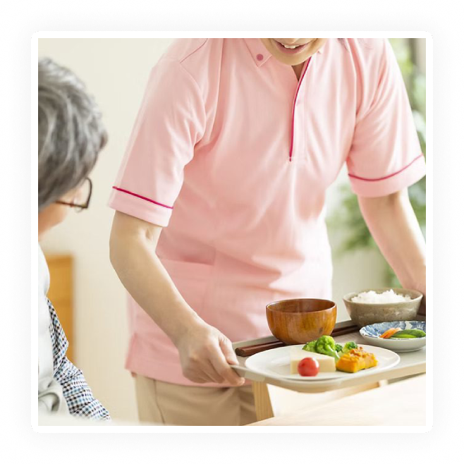 A caregiver serving a meal to an elderly person.